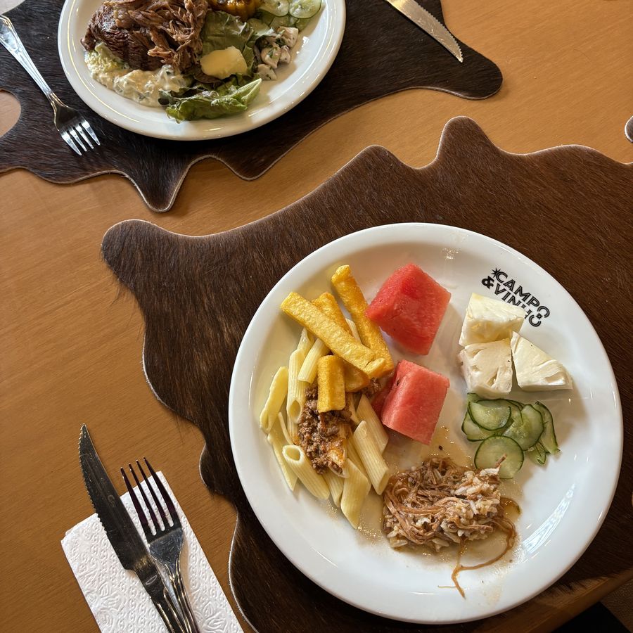 Pratos servidos no buffet sobre jogos americanos de couro, vistos de cima